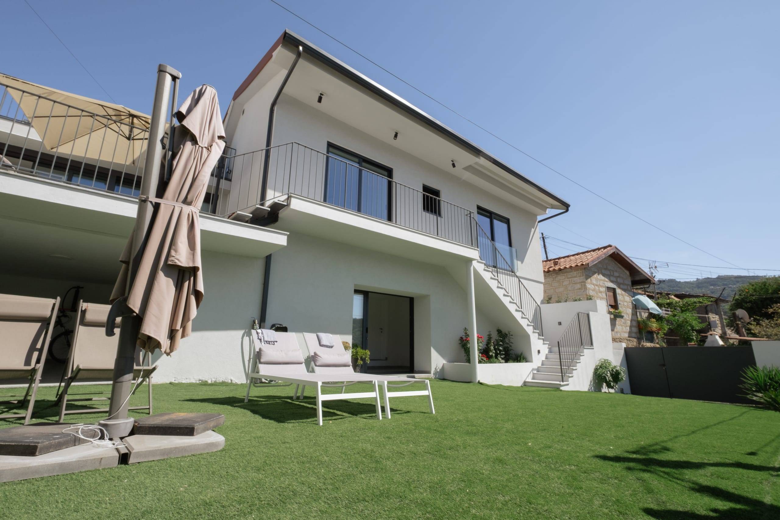 Fachada da Casa Miralago e jardim relvado com zona de estar