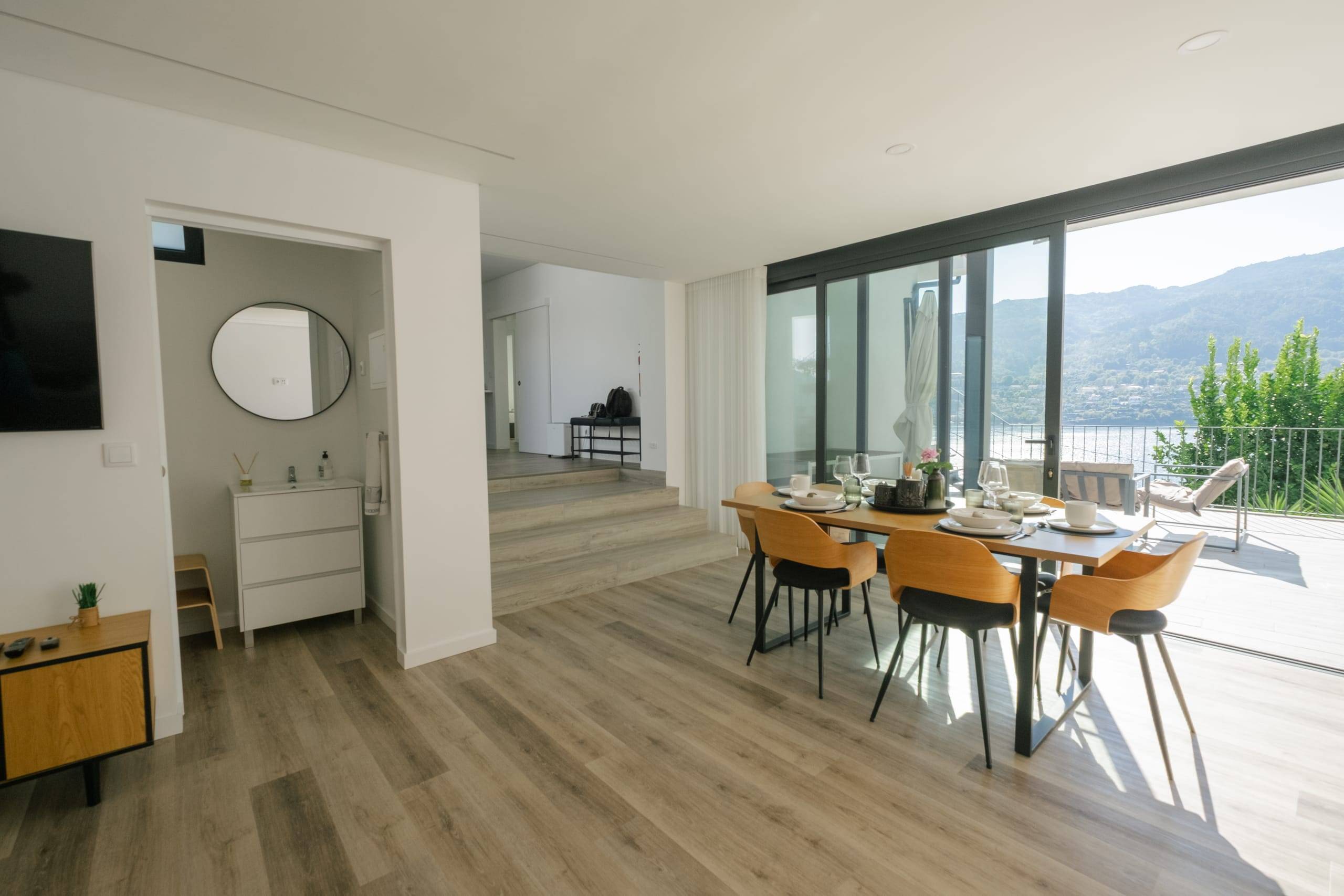 Sala de jantar luminosa com janelas de vidro para o terraço e o lago