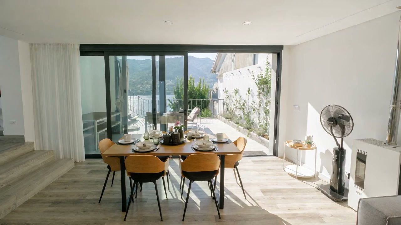 Sala de jantar da Casa Miralago aberta para o terraço com vista sobre a Barragem da Caniçada