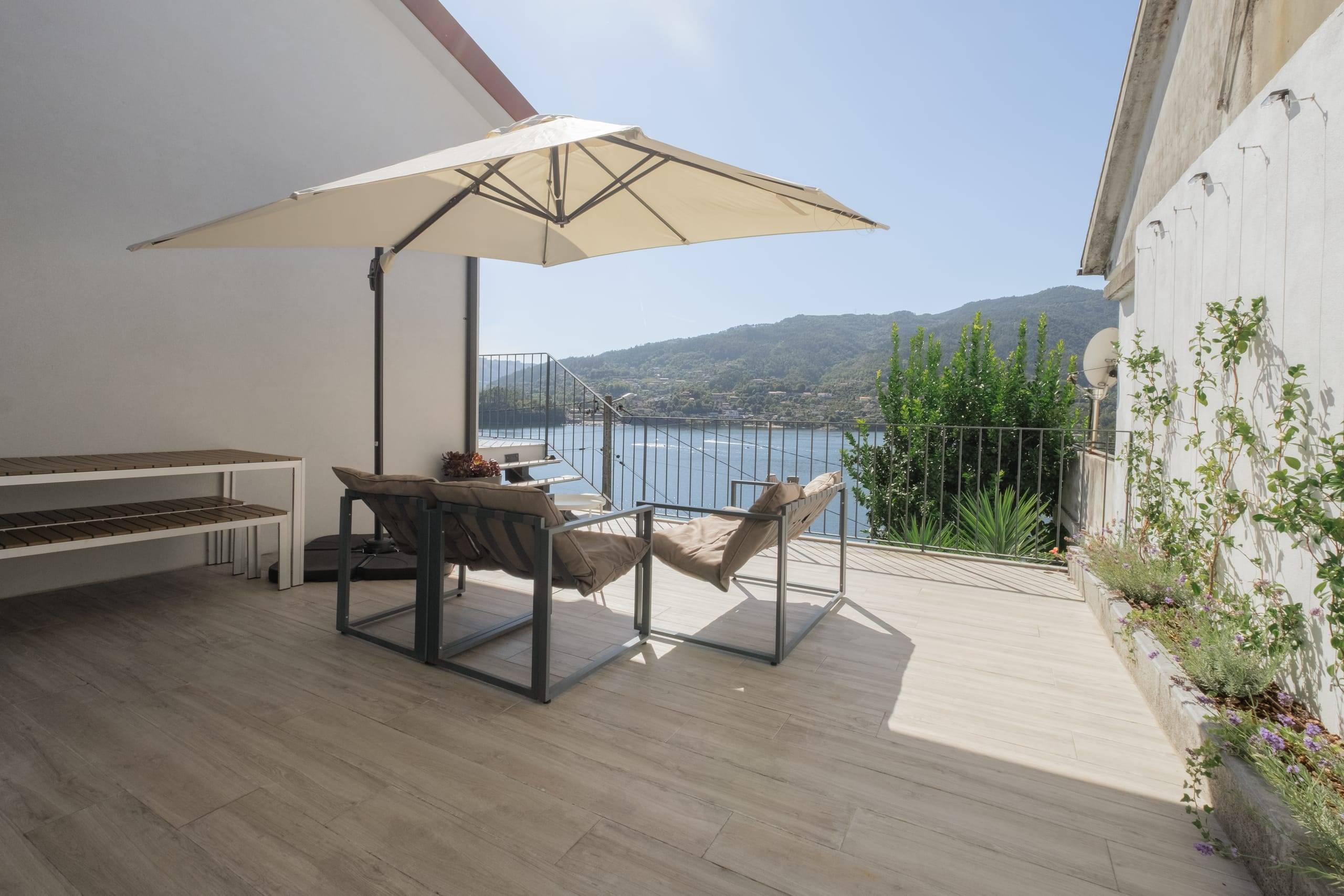 Terraço com cadeirões, guarda-sol e vista para o lago